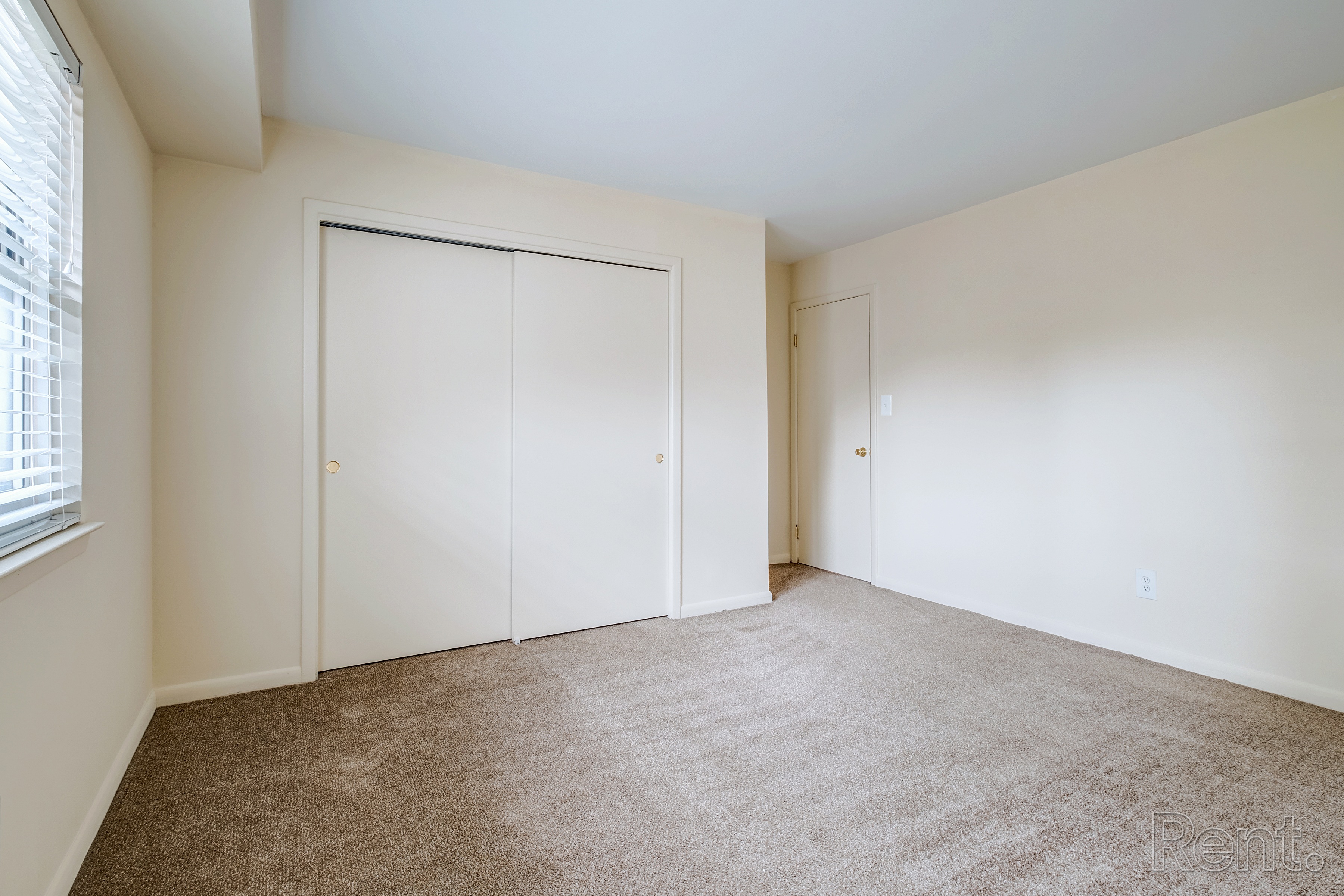 A room with a carpeted floor and two closets.