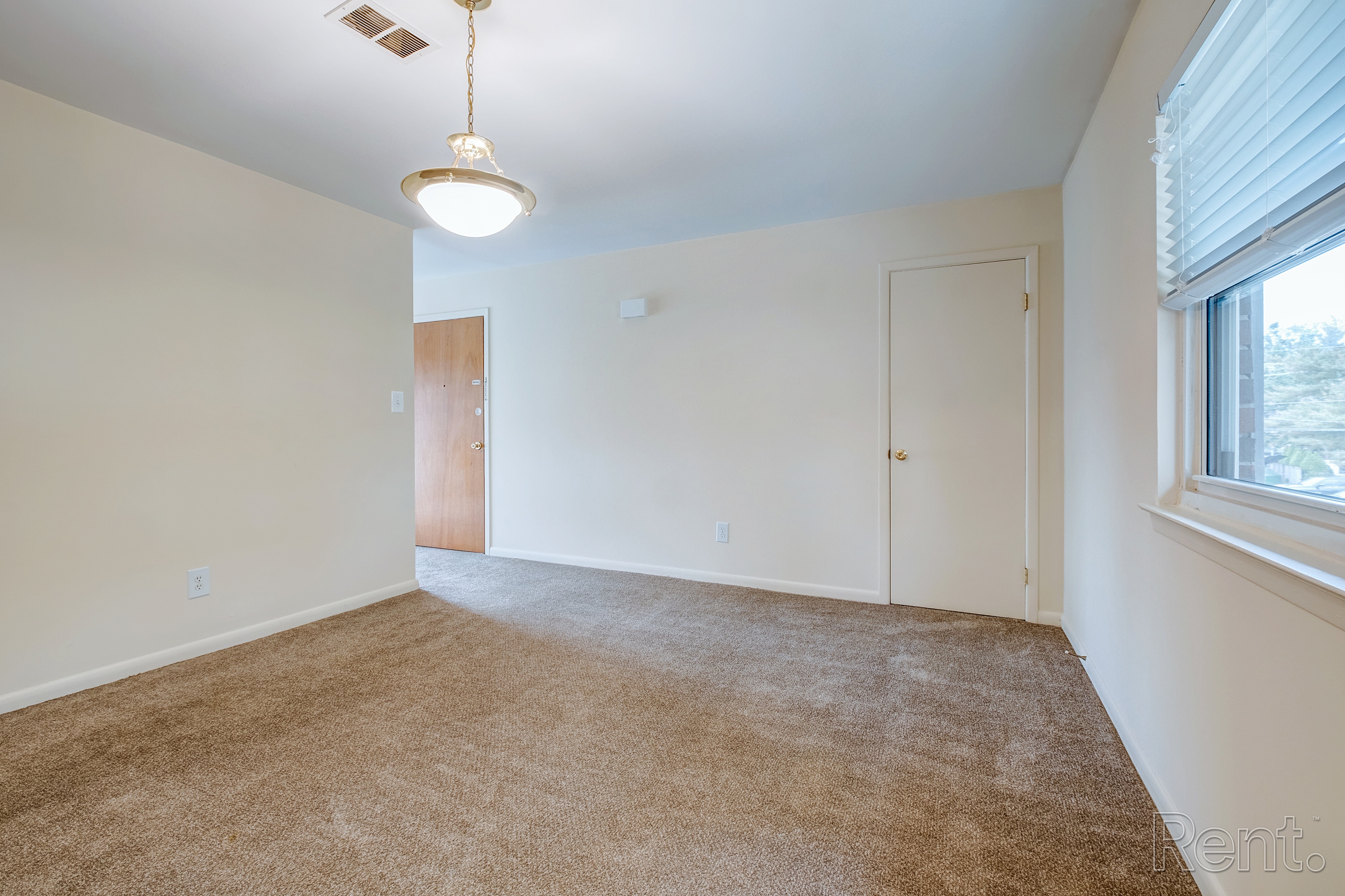 A carpeted room with a ceiling light and two doors.