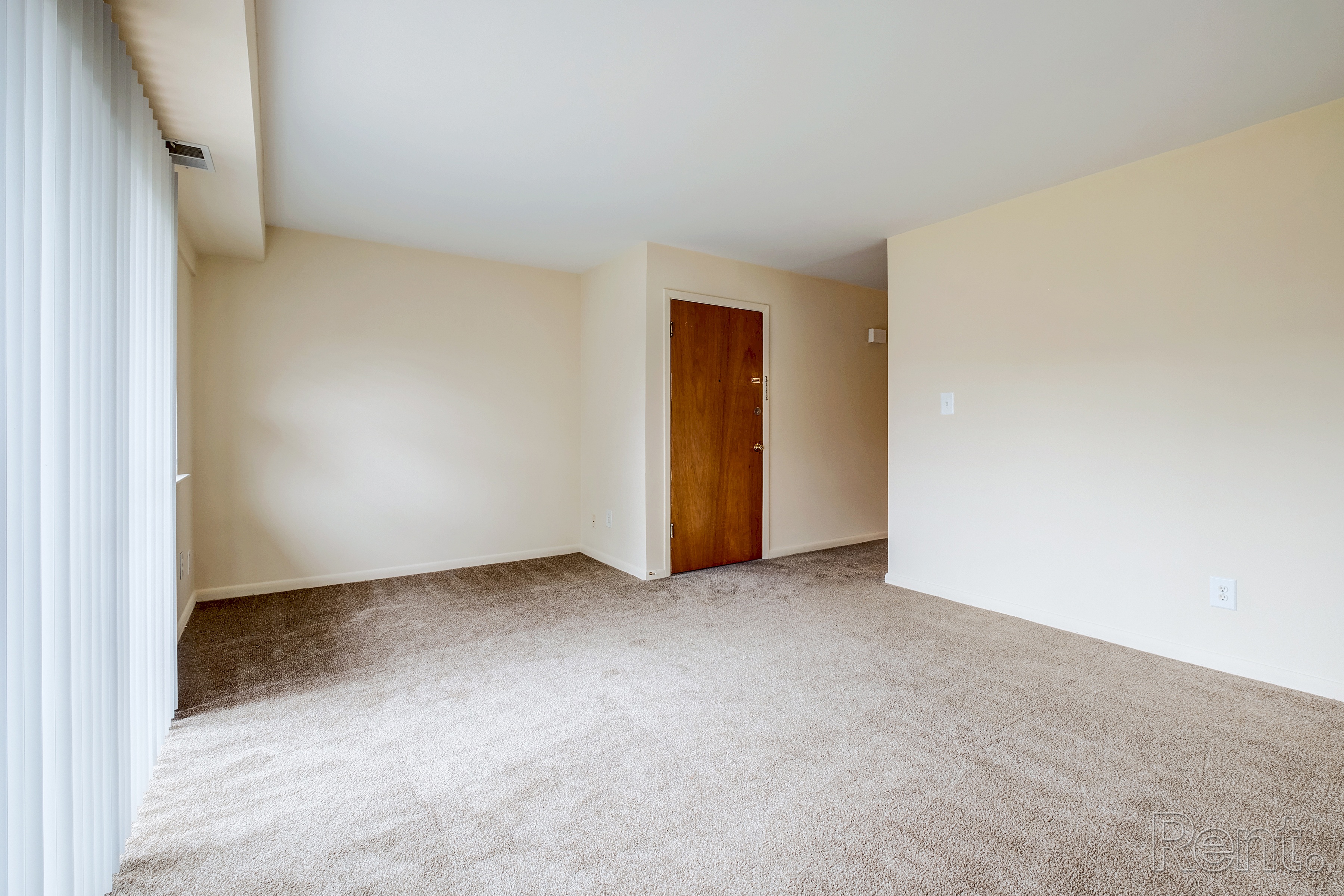 A room with a carpeted floor and a wooden door.