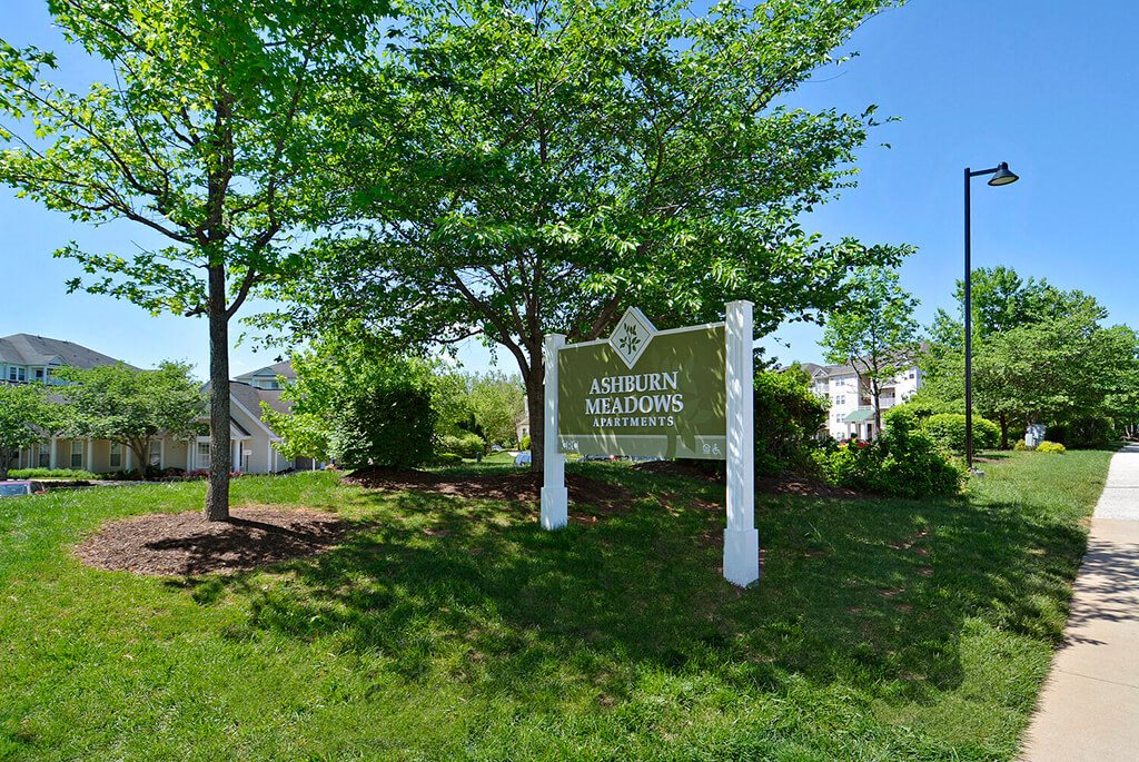 A sign for Ashdown Apartments stands in a grassy area.