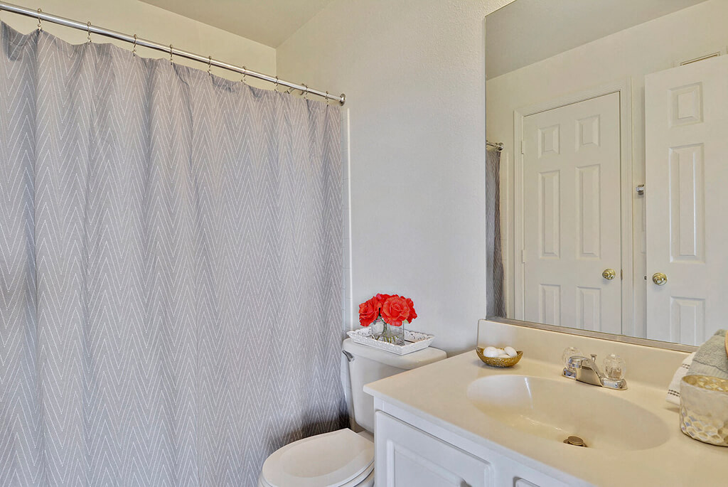 A bathroom with a white toilet, sink, and shower curtain.