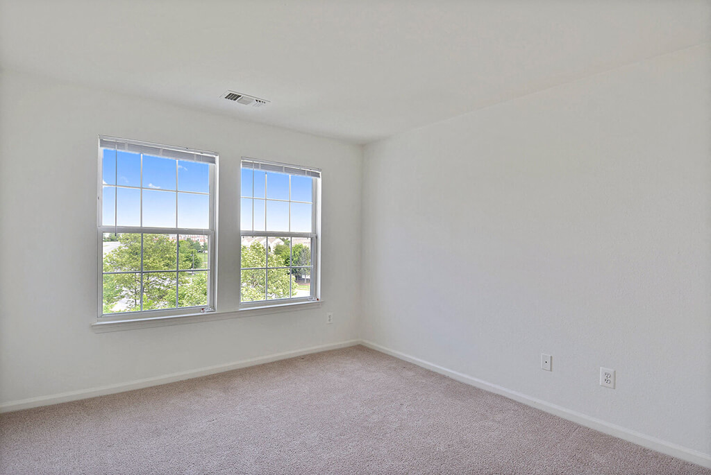 A room with two windows and carpeted floor.