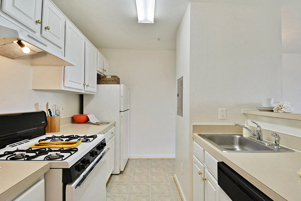A kitchen with a black stove top oven and white cabinets.