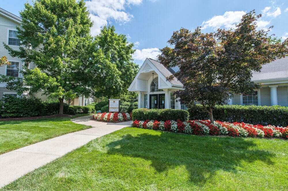 A white house with a green lawn and a sign in front.