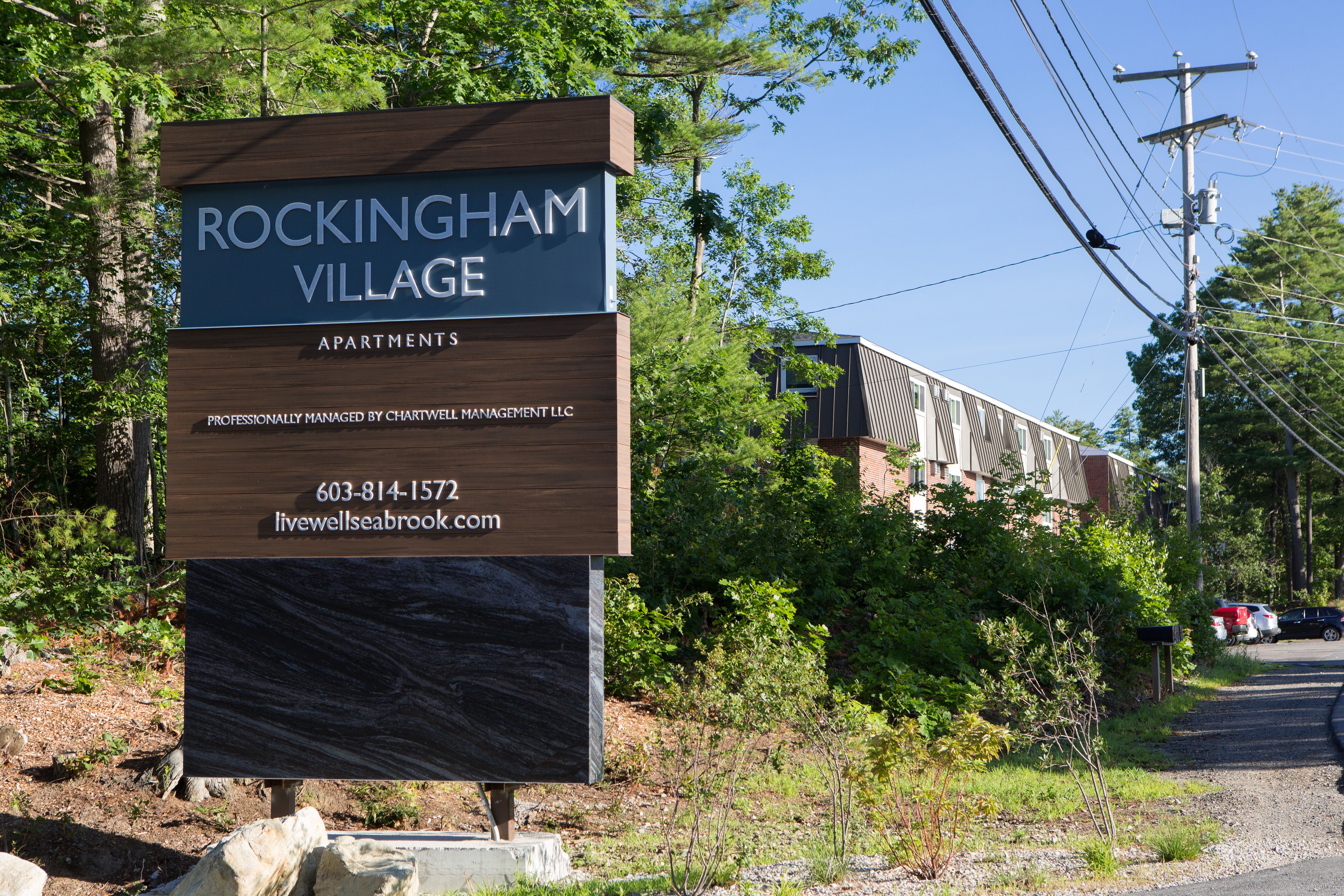 A sign for Rockingham Village Apartments sits in front of a building.