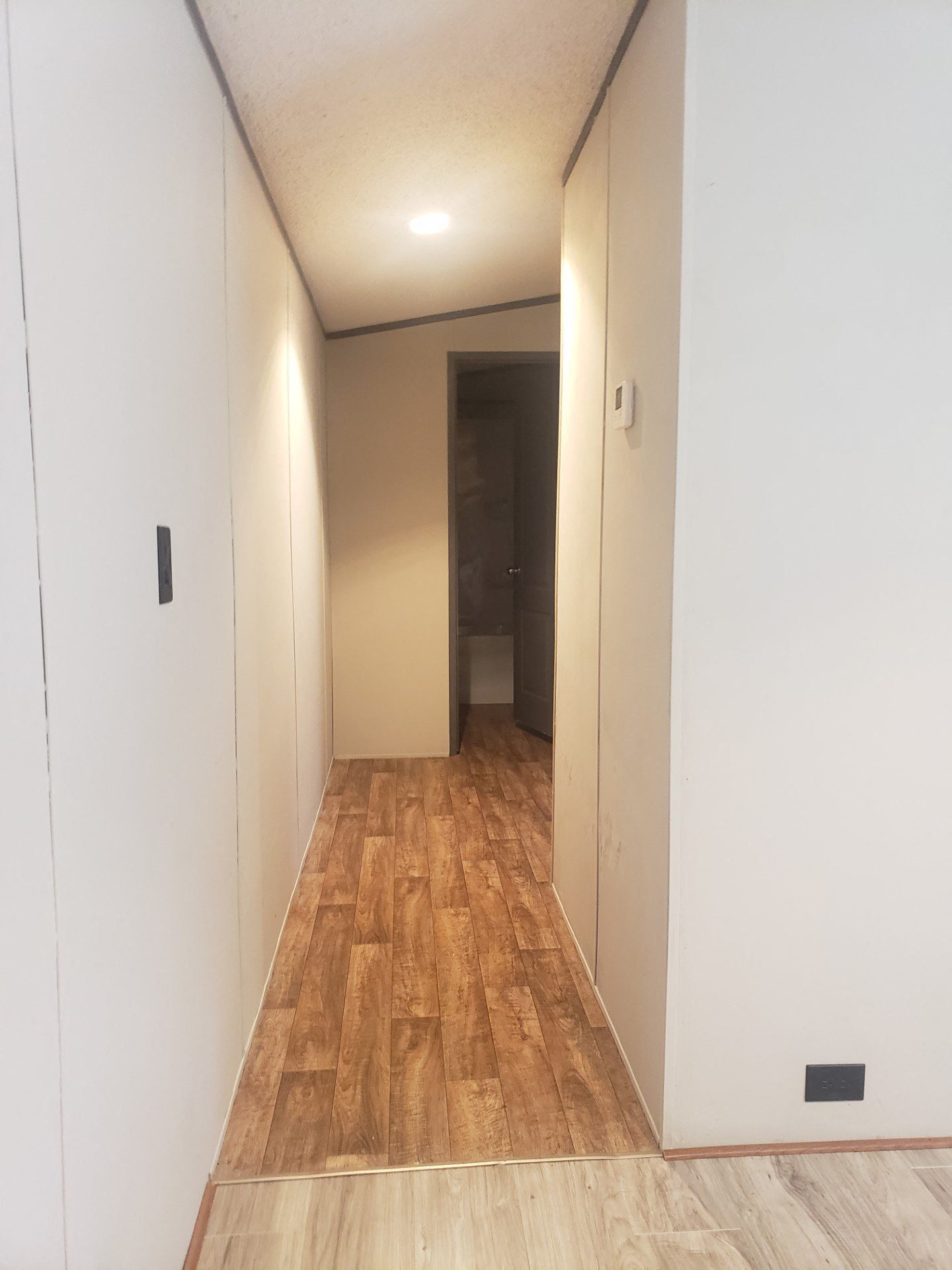 a very long hallway with white walls and wooden floors