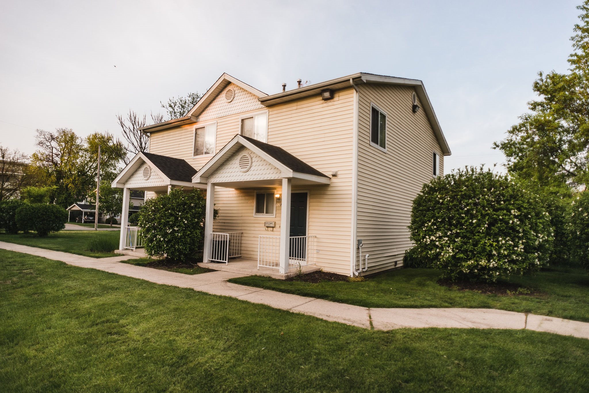 duplex with yellow siding and white trim grass