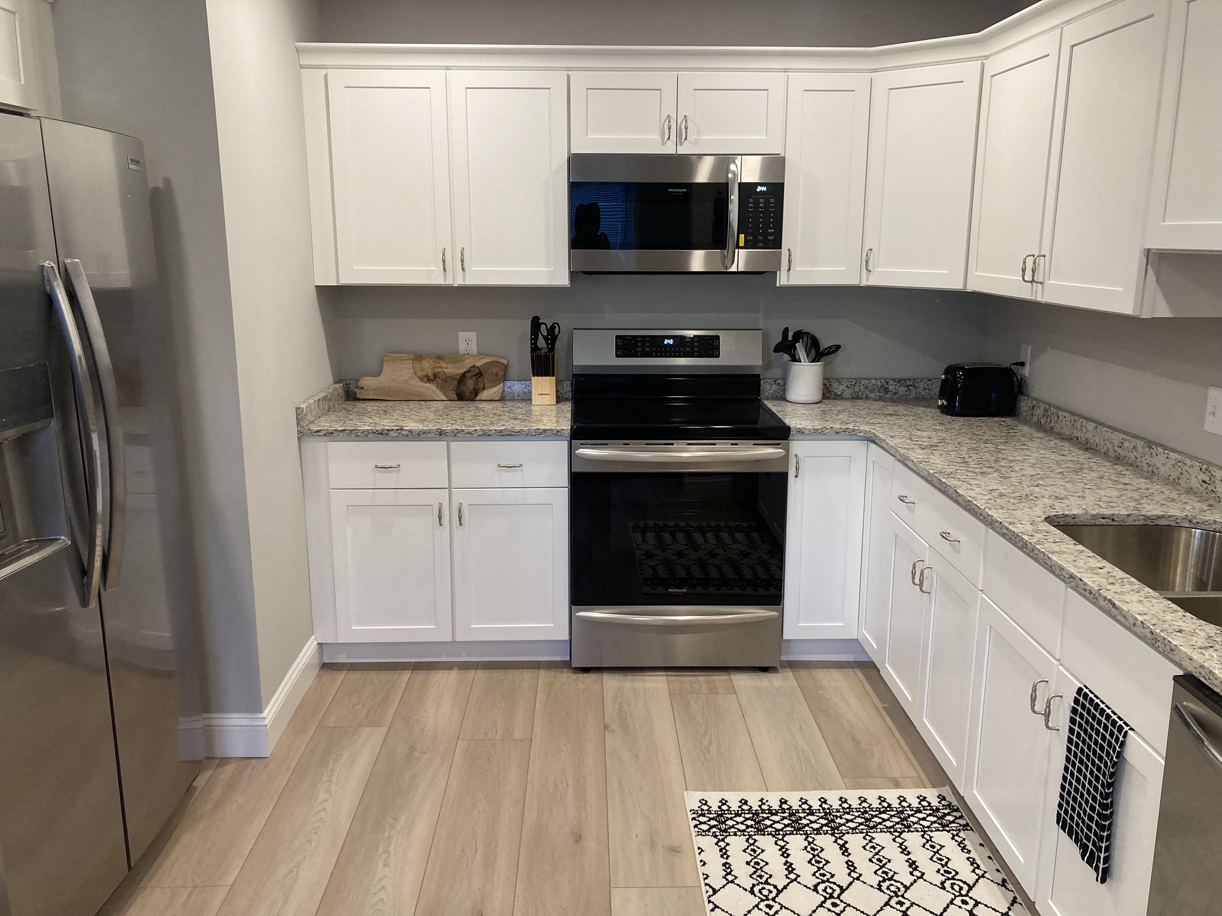 a white kitchen with stainless steel appliances and white cabinets