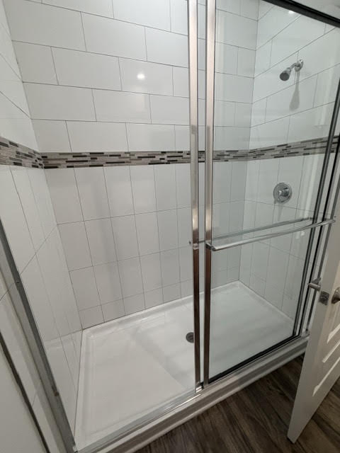 A glass shower door with a silver handle.