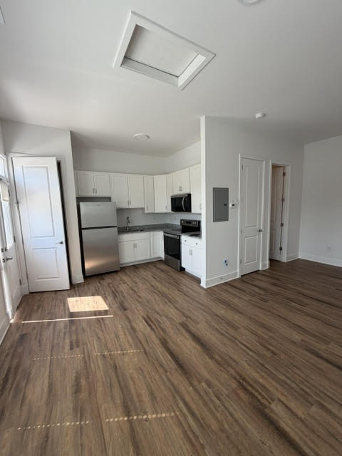 A kitchen with white cabinets and a wooden floor.