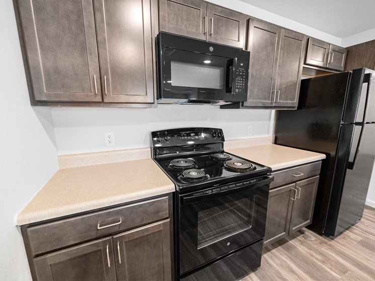 a kitchen with dark wood cabinets and black appliances  at Union at Wiley, Iowa, 52404