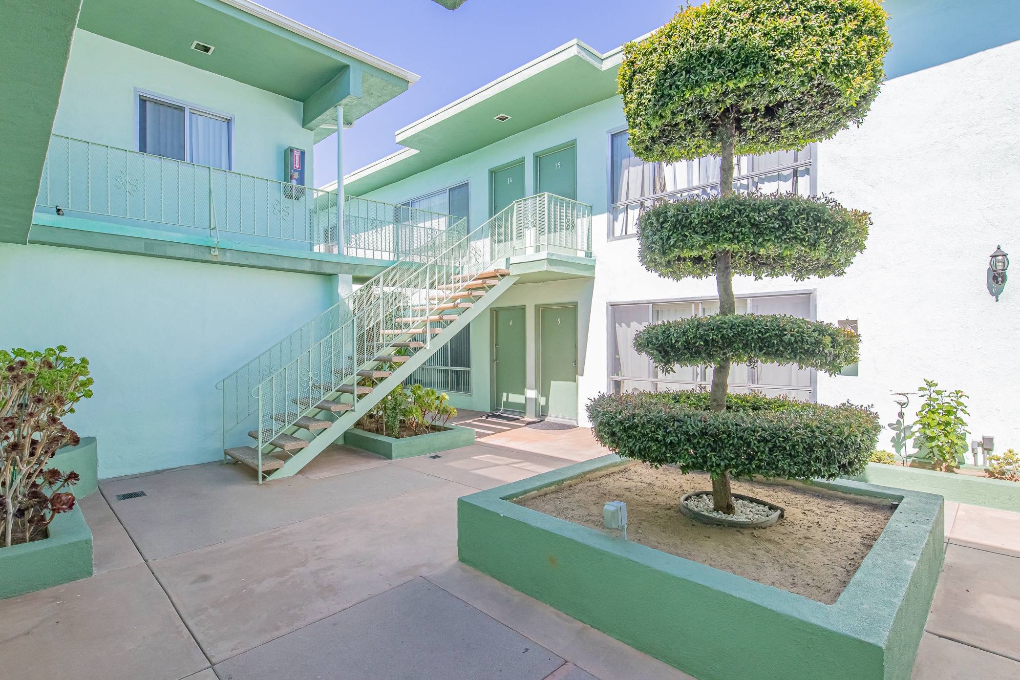 a building with stairs and a courtyard with a tree