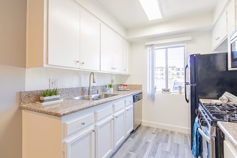 a kitchen with white cabinets and granite counter tops and a black stove and refrigerator