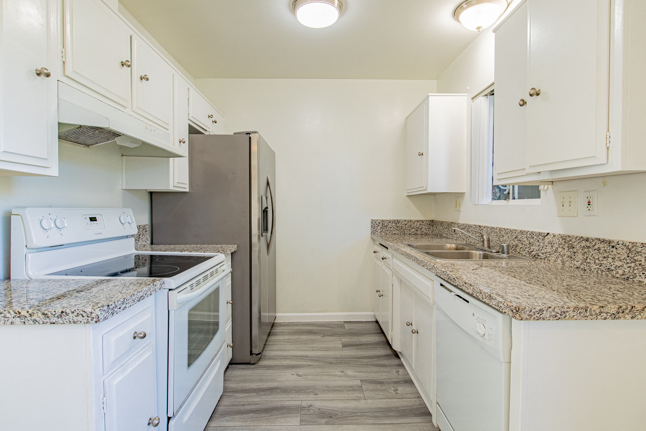 an empty kitchen with white appliances and granite counter tops