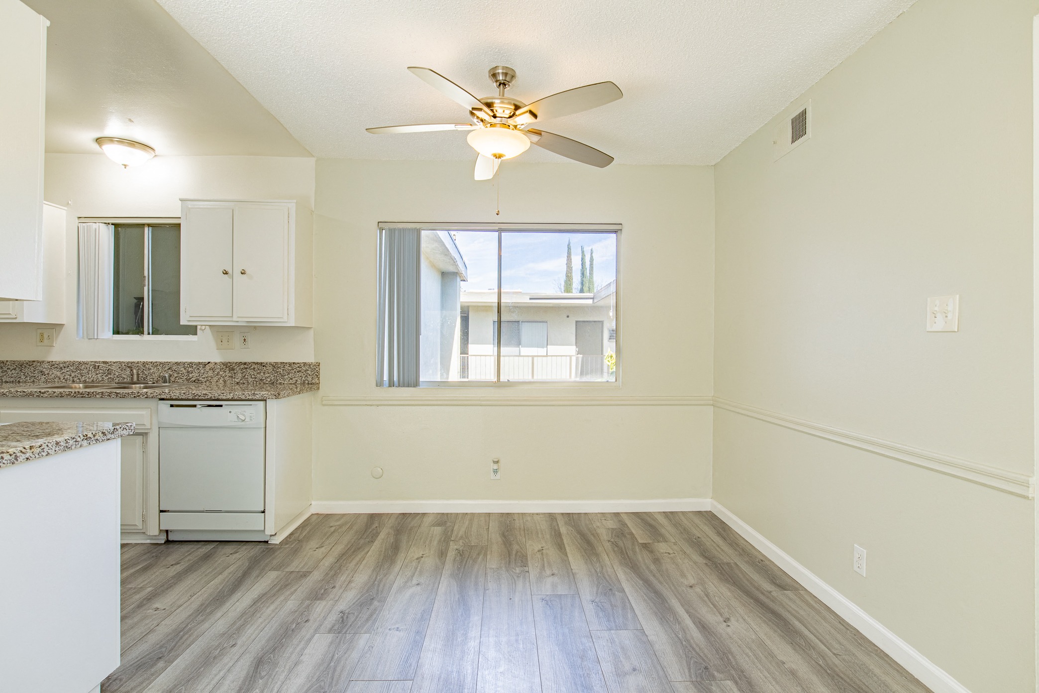 an empty kitchen with a ceiling fan and a window