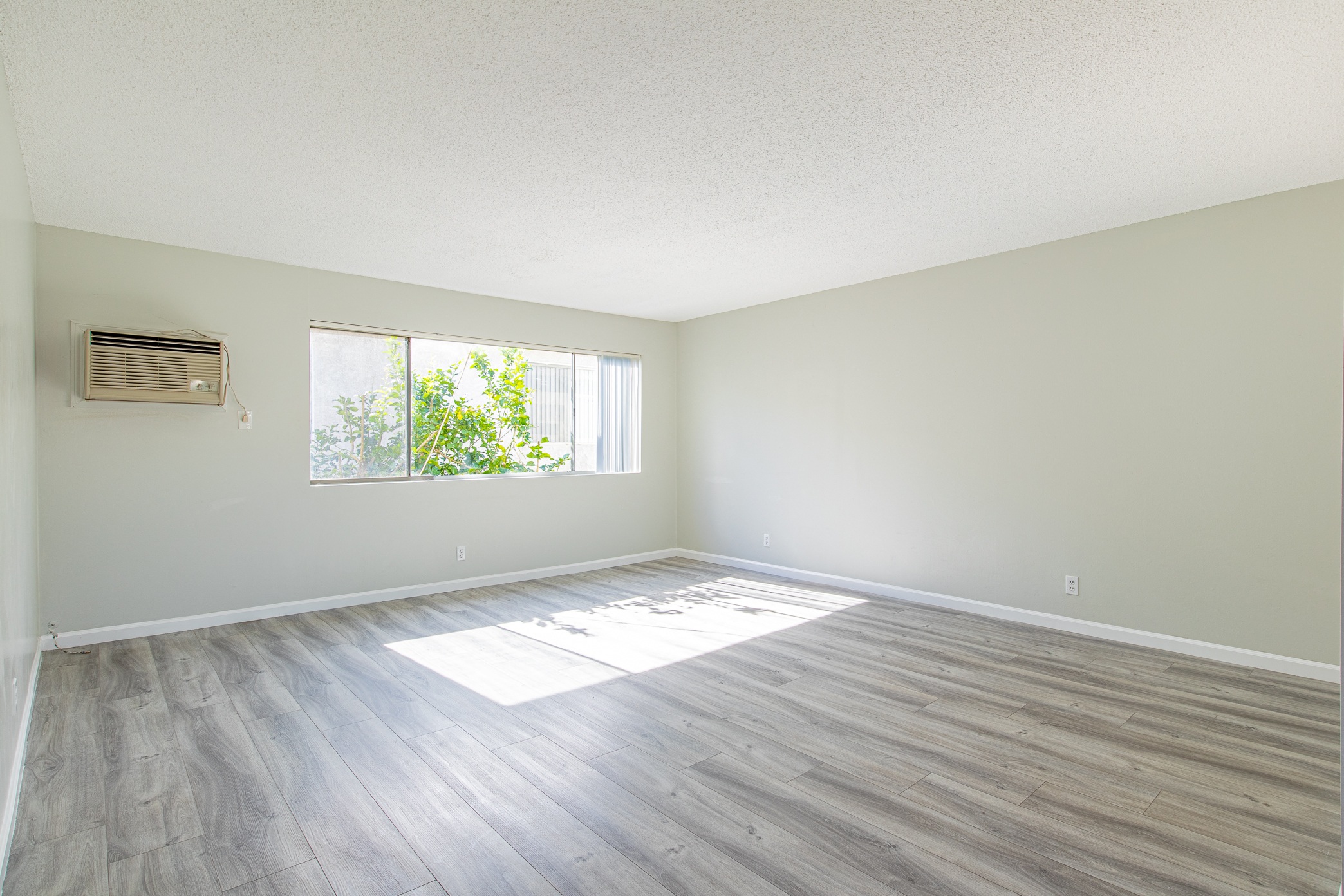 an empty living room with wood floors and a window