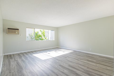 an empty living room with wood floors and a window