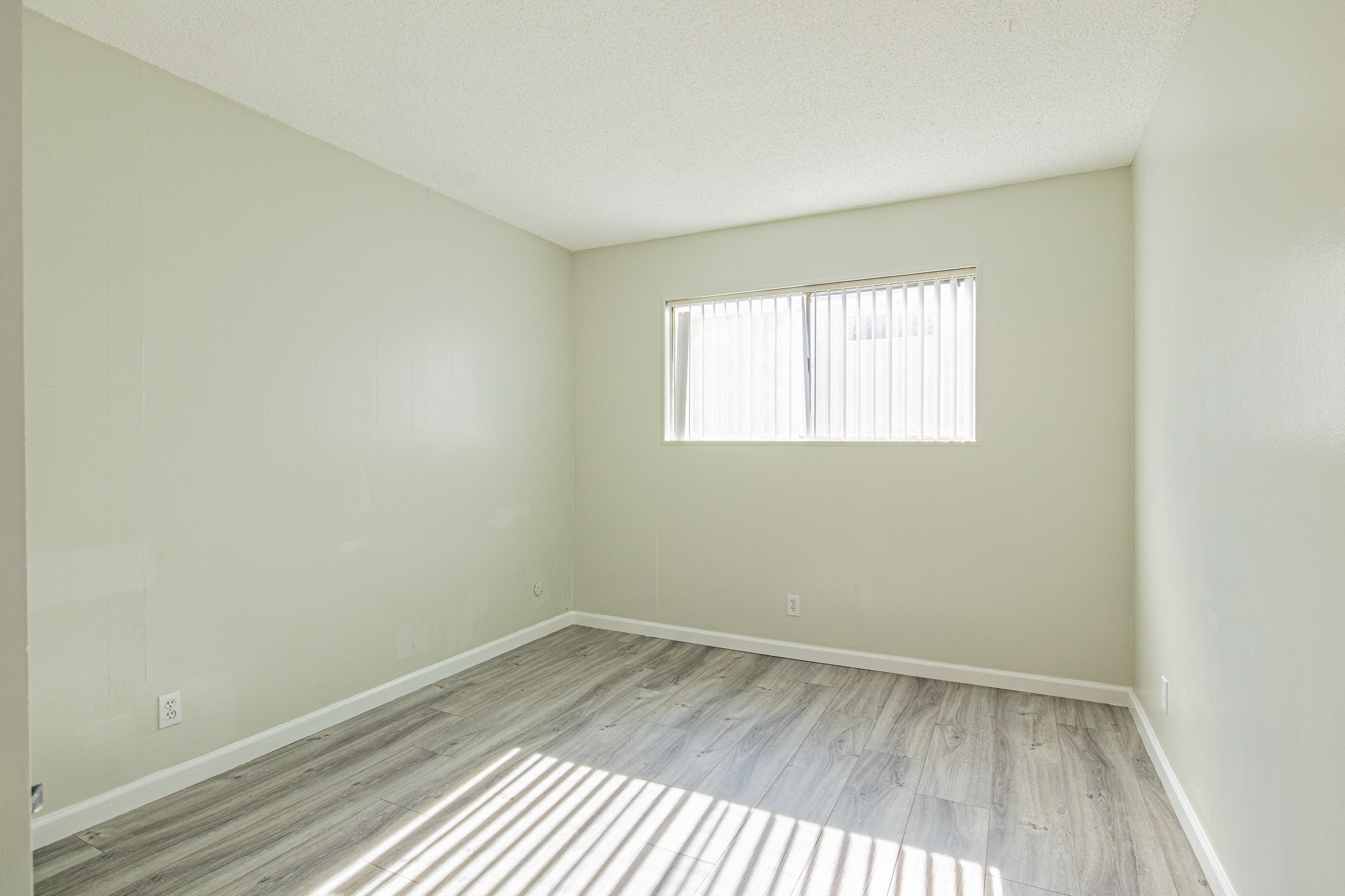 an empty room with wood floors and a window