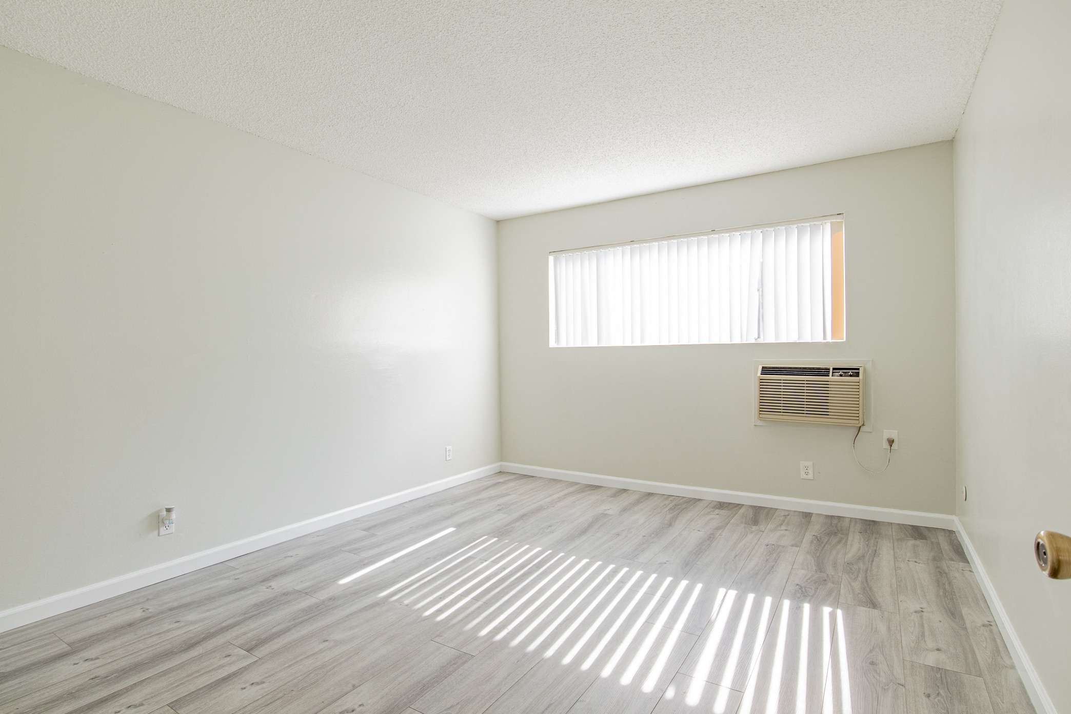an empty living room with wood flooring and a window