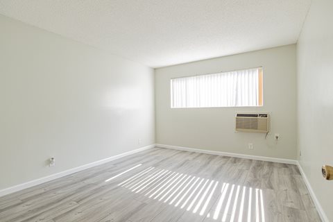 an empty living room with wood flooring and a window