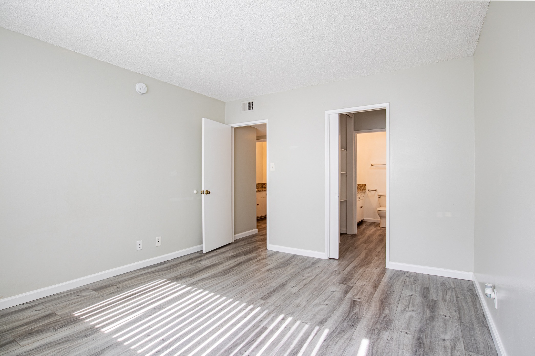 a spacious living room with white walls and wood flooring