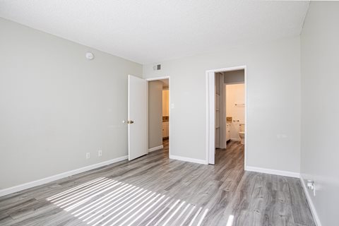a spacious living room with white walls and wood flooring