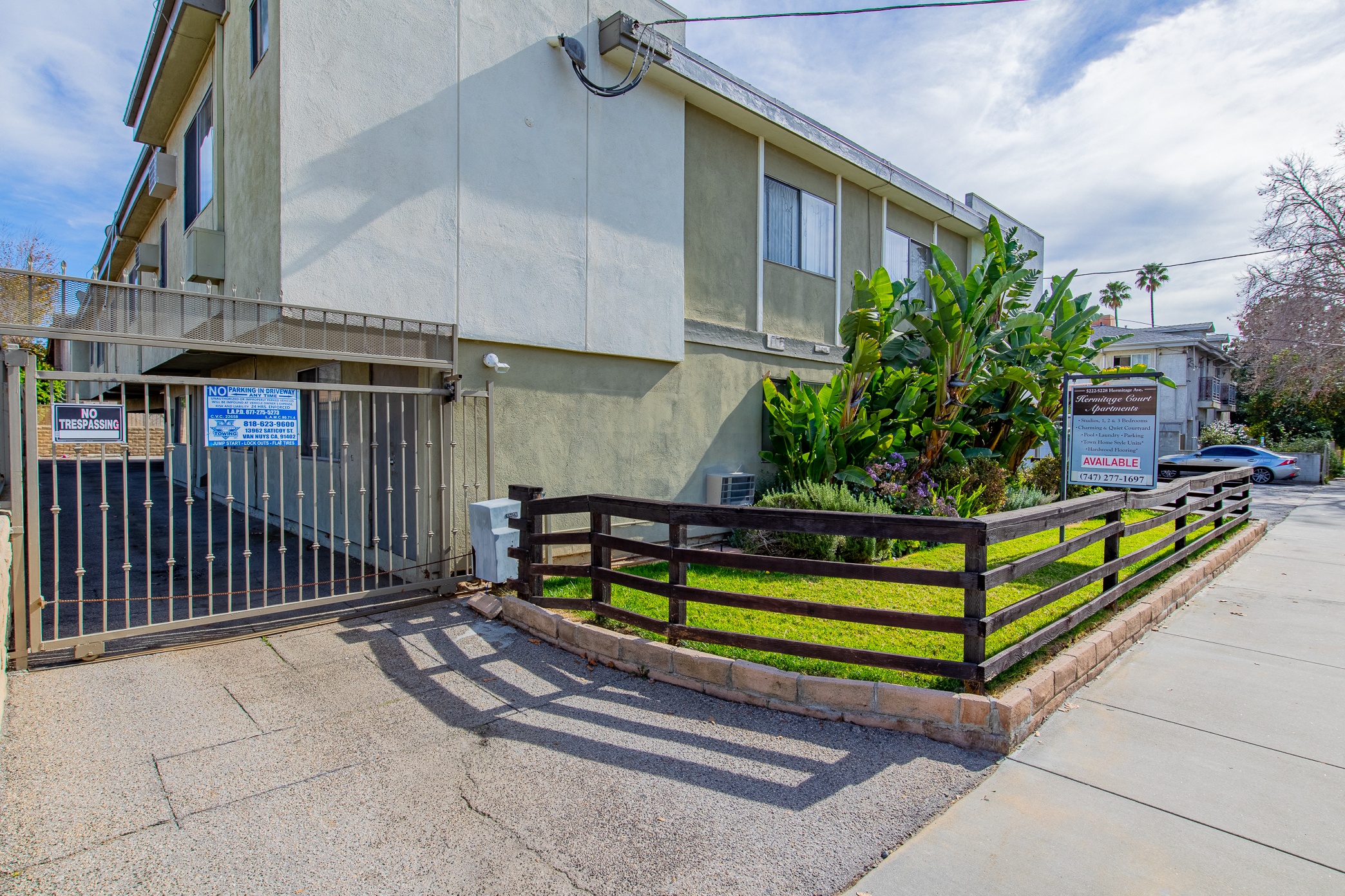 an apartment building with a fence and a sidewalk in front of it