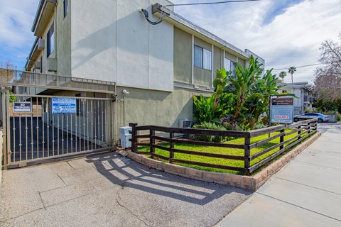 an apartment building with a fence and a sidewalk in front of it