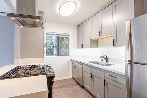an empty kitchen with stainless steel appliances and white cabinets