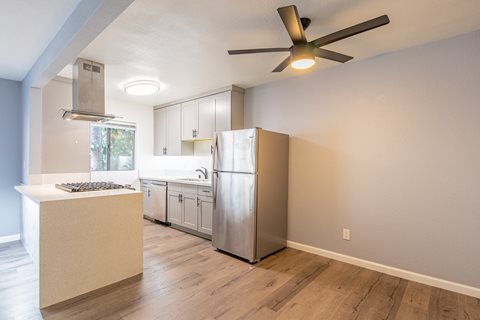 an empty kitchen with a stainless steel refrigerator and a ceiling fan