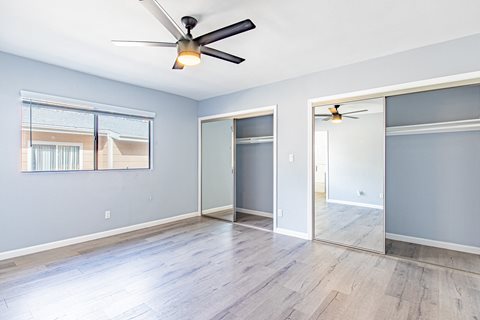 an empty living room with a ceiling fan and a mirror