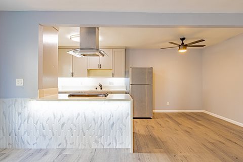 a kitchen with a white counter top and a stainless steel refrigerator