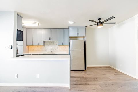 an empty kitchen with white cabinets and a refrigerator