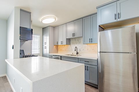 an empty kitchen with stainless steel appliances and white countertops