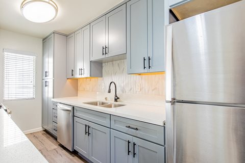 a kitchen with blue cabinets and a stainless steel refrigerator