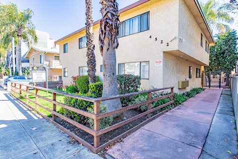 an apartment building with a sidewalk and palm trees