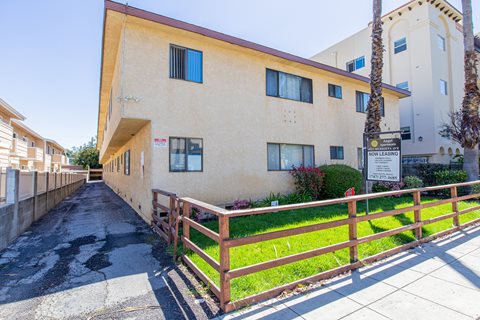 an apartment building with a fence and a sidewalk in front of it
