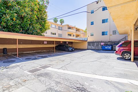 a parking lot with a building and a red car in front of it