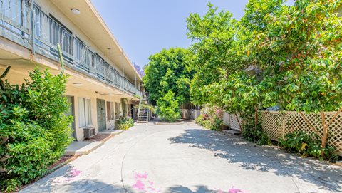an empty sidewalk next to a building with trees