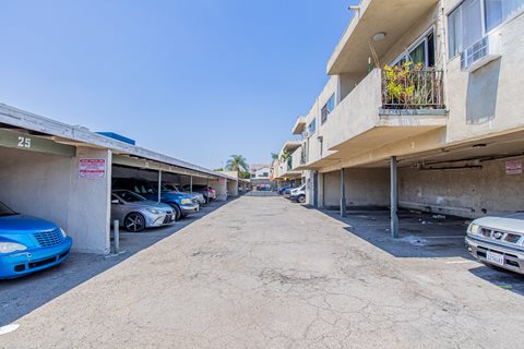 the entrance to the parking lot of a building with cars parked on both sides