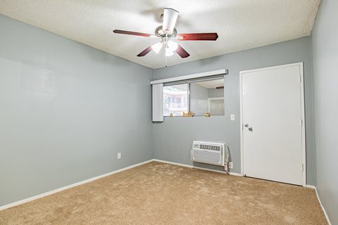 A room with a ceiling fan and a window with blinds.