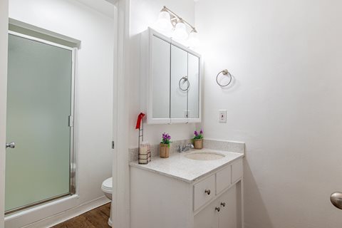 A white bathroom with a sink and mirror.