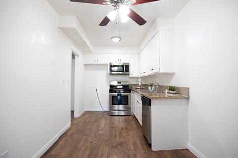 A kitchen with a fan on the ceiling and a stainless steel oven.