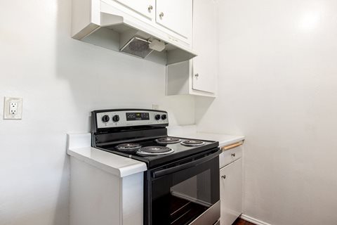 A white stove top oven with a black oven door sits on a white counter.