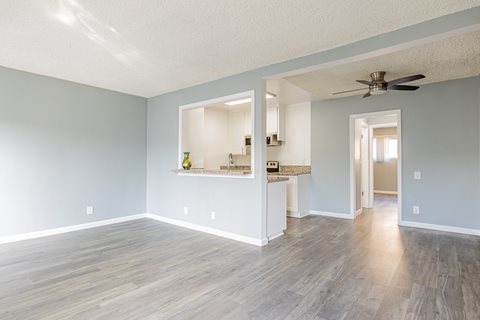 A room with a ceiling fan and a long wooden floor.