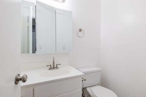A white bathroom with a toilet, sink, and medicine cabinet.