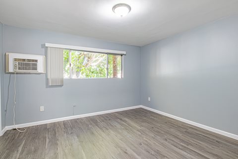 A room with a window and a wall-mounted air conditioning unit.