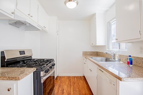 A kitchen with a black stove top oven and white cabinets.