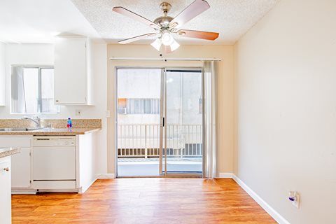 A kitchen with a fan and a view of a balcony.