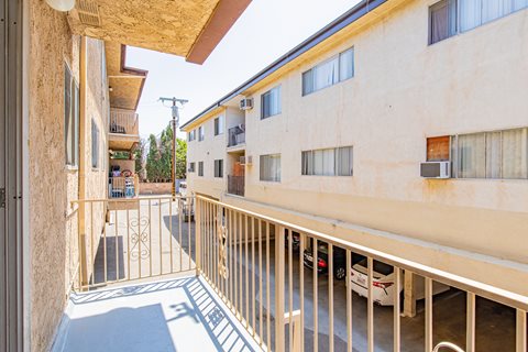 A view of a balcony with a metal railing and a car parked in the driveway.
